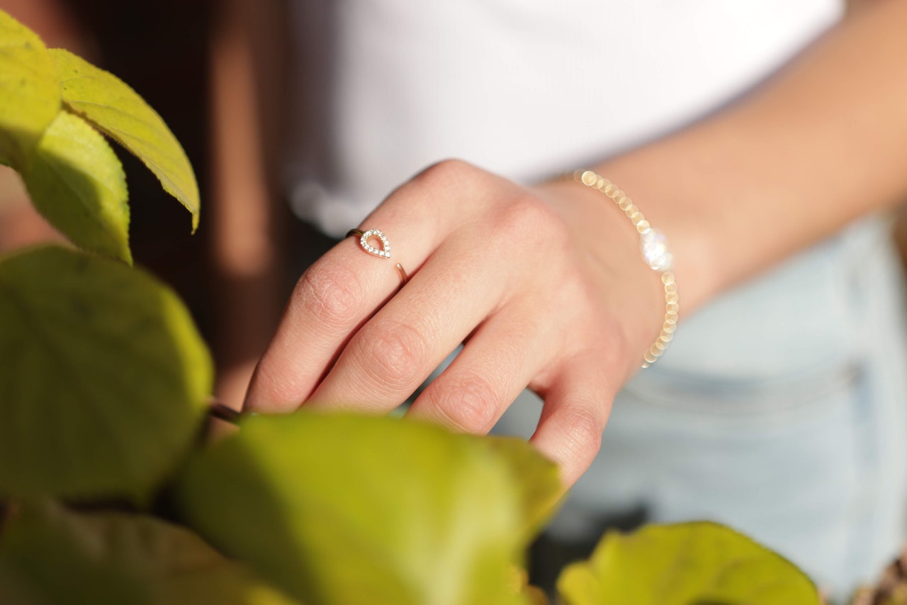 Girl in white shirt wearing a gold ring with diamond details