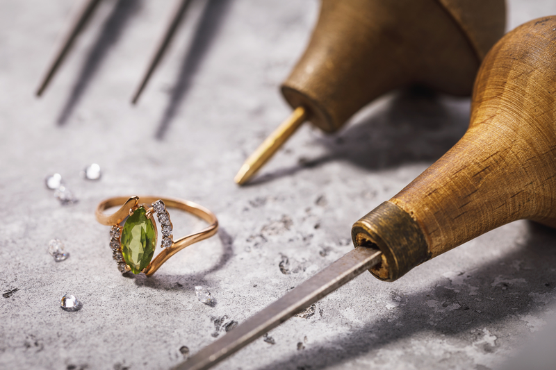 Gold ring with precious stones on the table, surrounded by jewel Gold ring with precious stones on the table, surrounded by jewelry repair tools, close-up