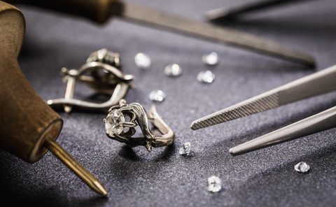 Earrings with a stone on the table, surrounded by tools for the repair of jewelry